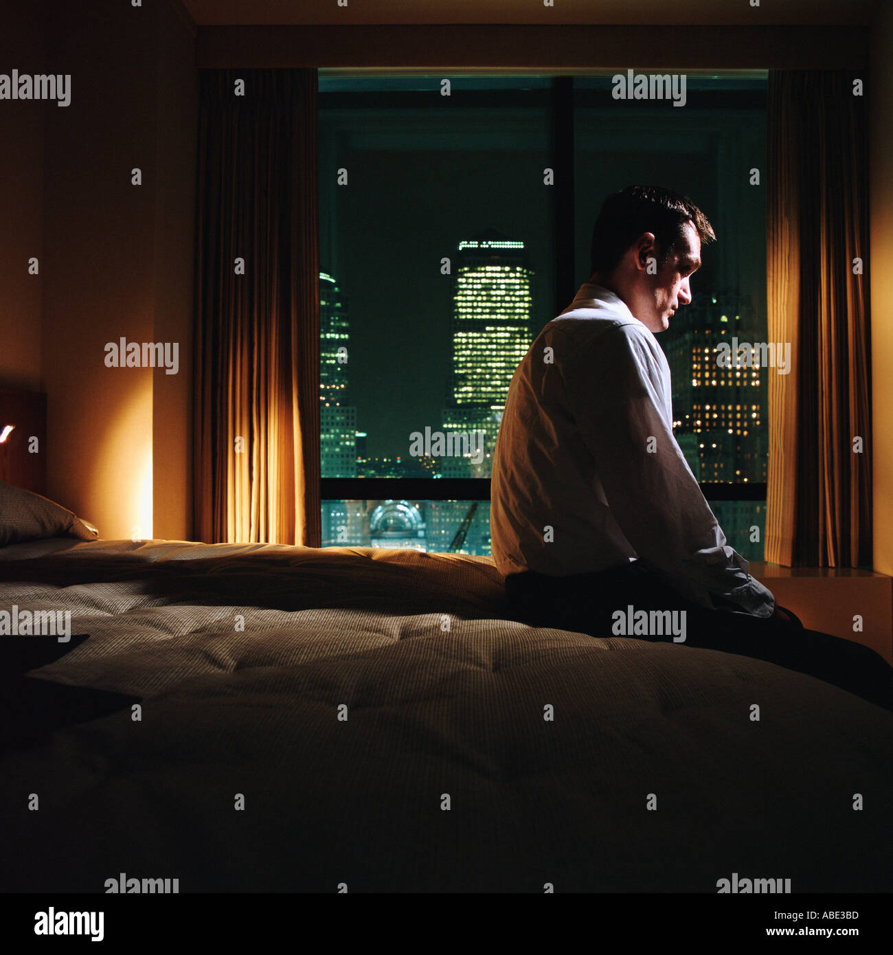 Serious looking man sitting on bed Stock Photo