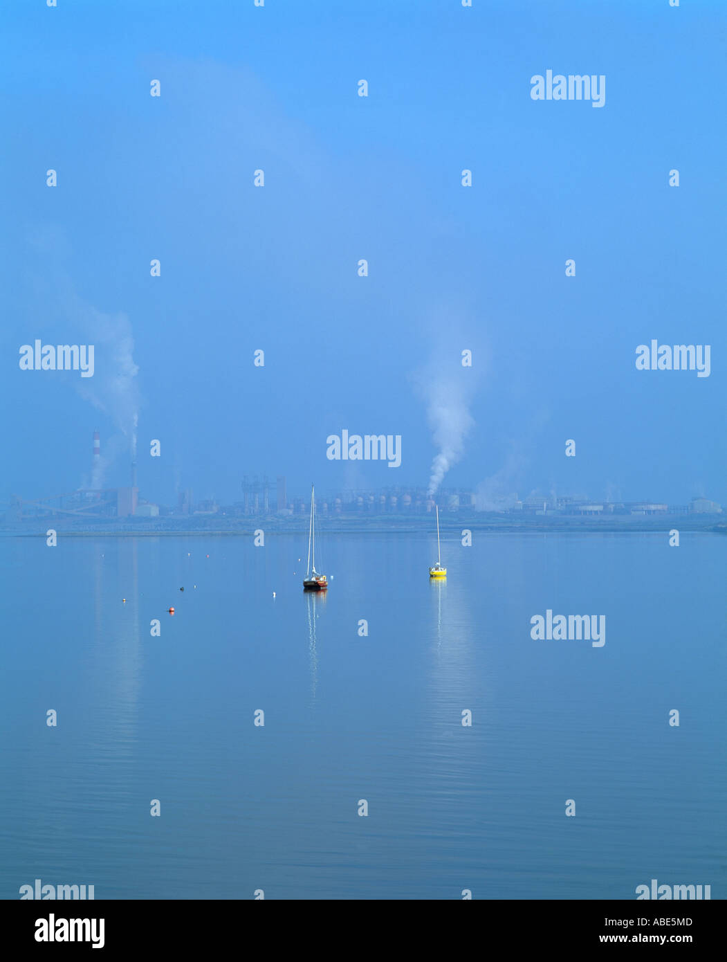small sailing boats anchored on river shannon with aughanish alumina plant in the background, Stock Photo