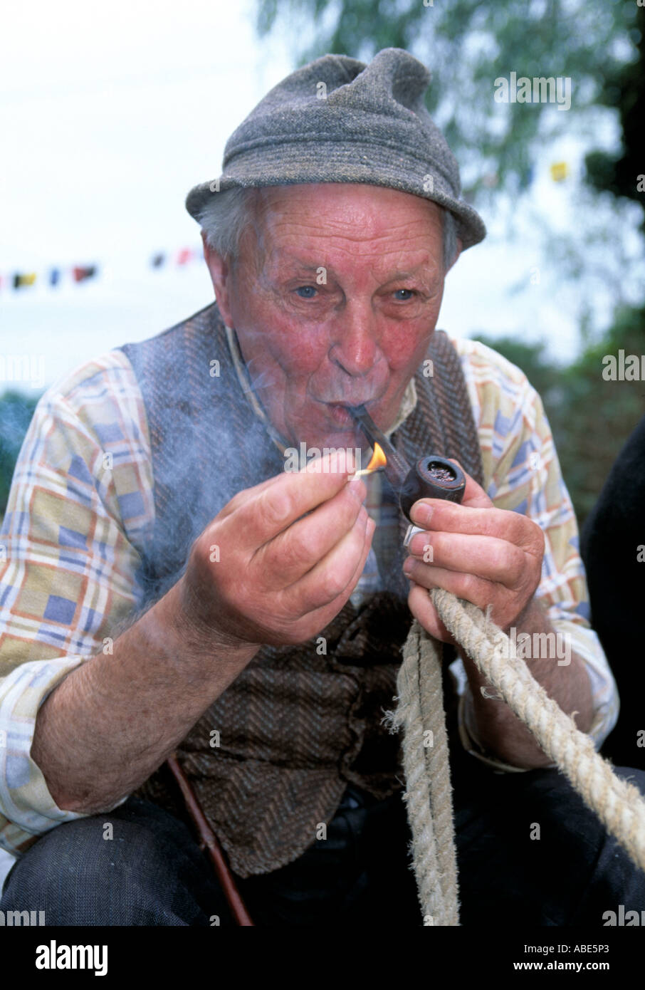 elderly man surrounded lighting his pipe and engulfed in the smoke ...