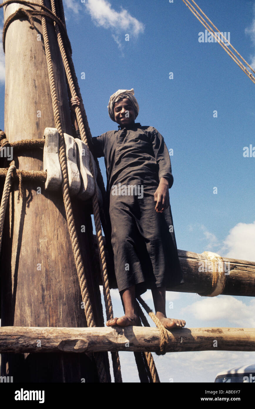 The youngest member of an Arab dhow crew poses beside the ship's great