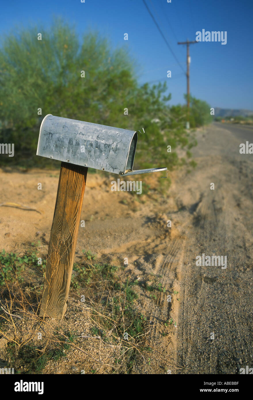 An old metal mailbox on a wooden post at the side of a rural country