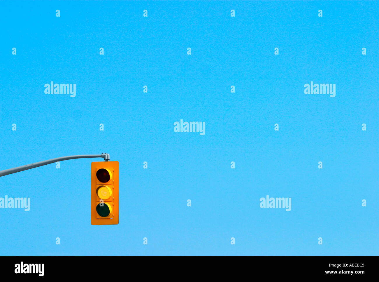 A traffic light signal with the yellow light on and with a clear blue