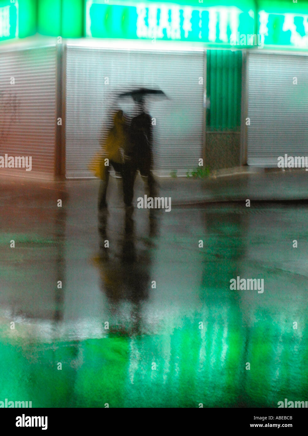 Motion blurred silhouettes of two people with an umbrella walking on a ...