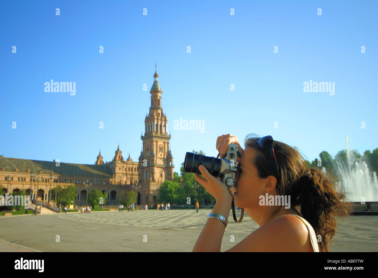 Young woman shooting with an old film camera in the Plaza de Espana of