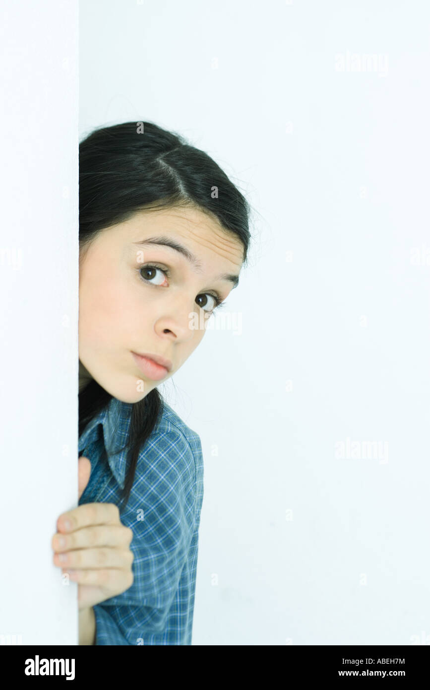 Teenage girl looking around corner, portrait Stock Photo