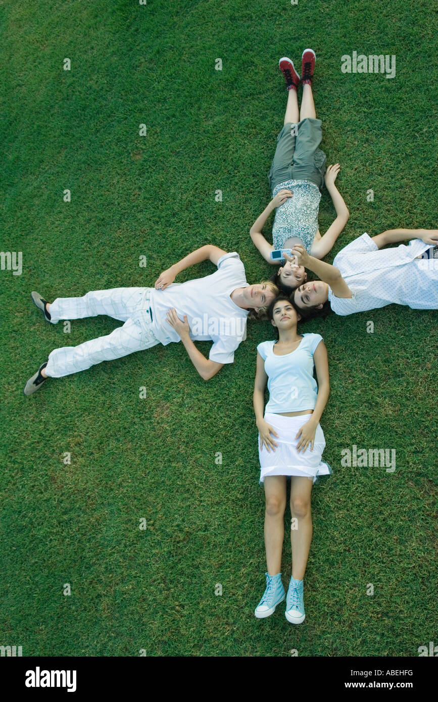 Group of young friends lying on grass with heads together Stock Photo
