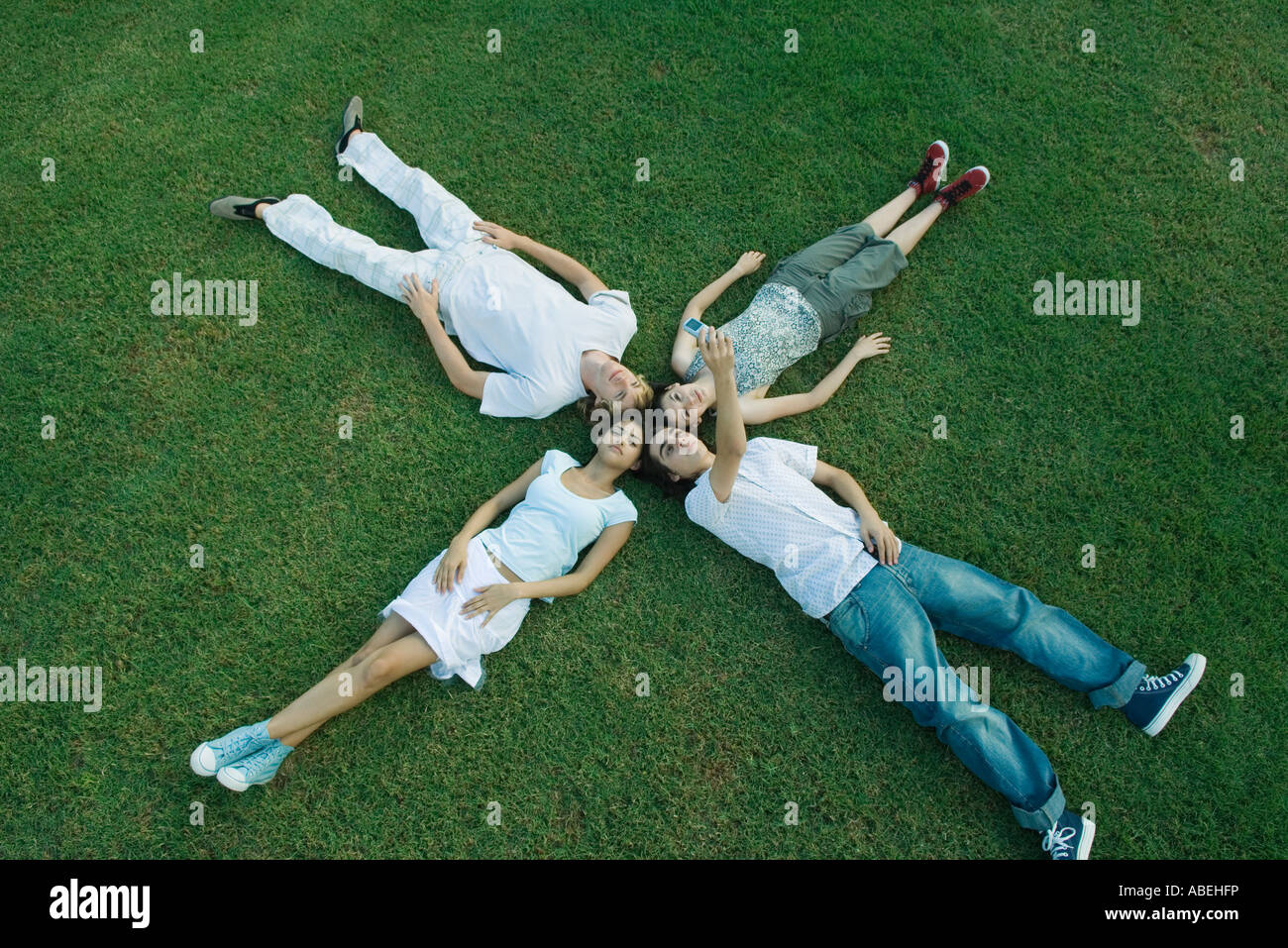 Group of young friends lying on grass, heads together Stock Photo