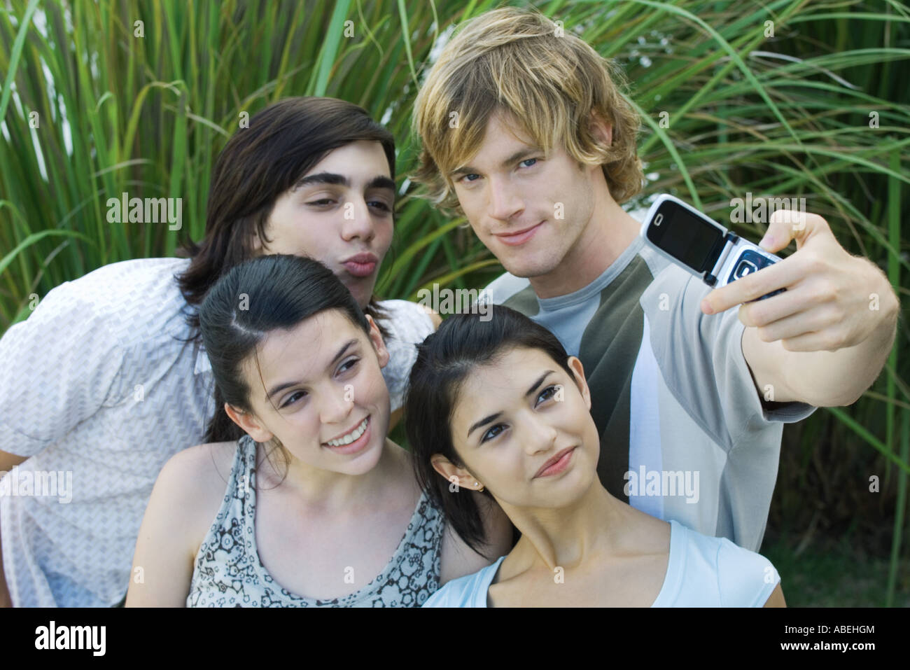 Group of young friends posing while man takes photo with cell phone Stock Photo