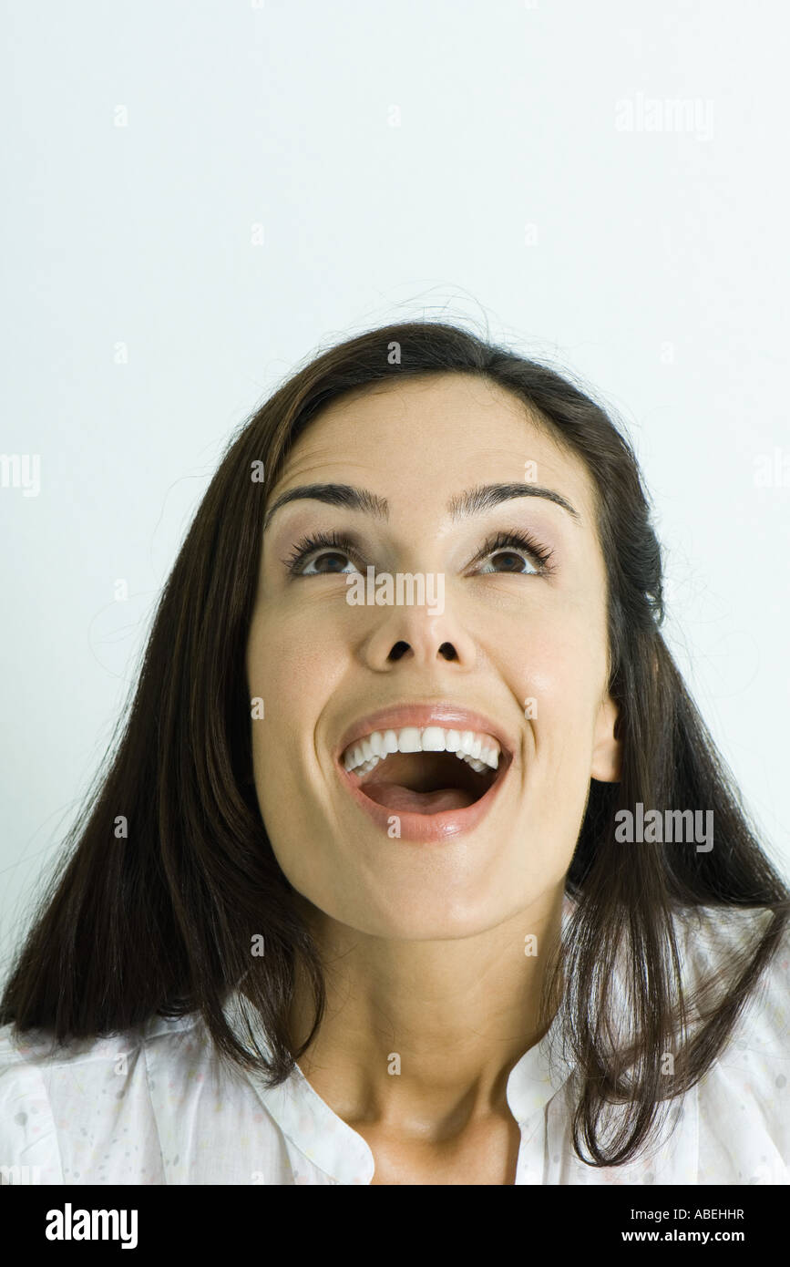 Woman looking up with mouth wide open, head and shoulders, portrait Stock Photo