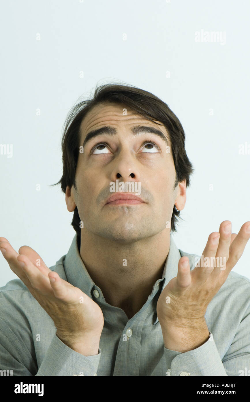 Man looking up and holding up hands, head and shoulders, portrait Stock Photo