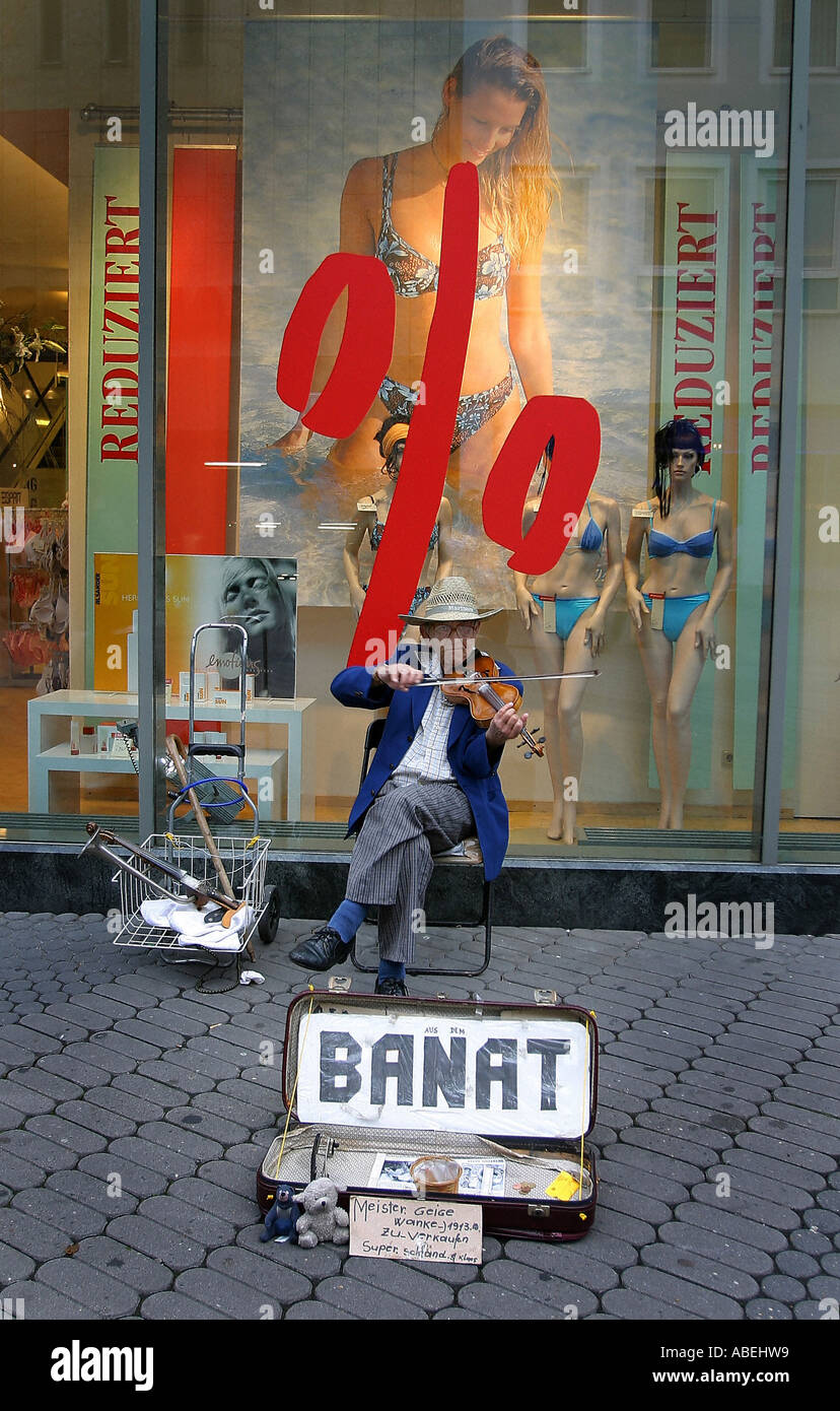Road musician from the Banat in front of a shop window with sale Stock Photo