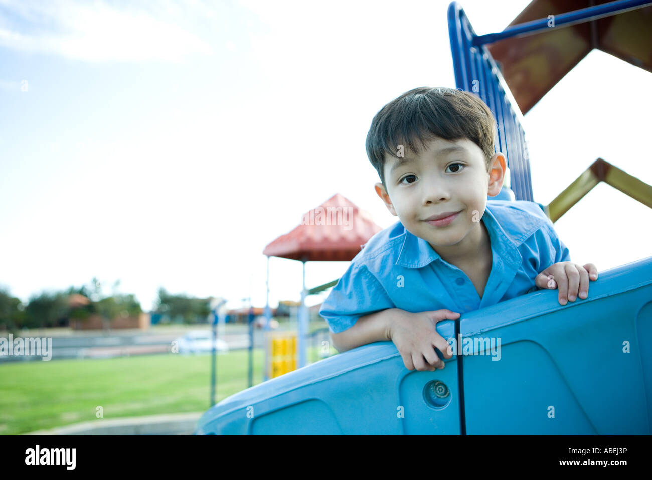 Boy on playground equipment, smiling at camera Stock Photo - Alamy