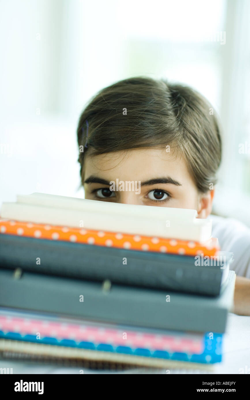 Teen girl looking at camera over stack of books Stock Photo - Alamy