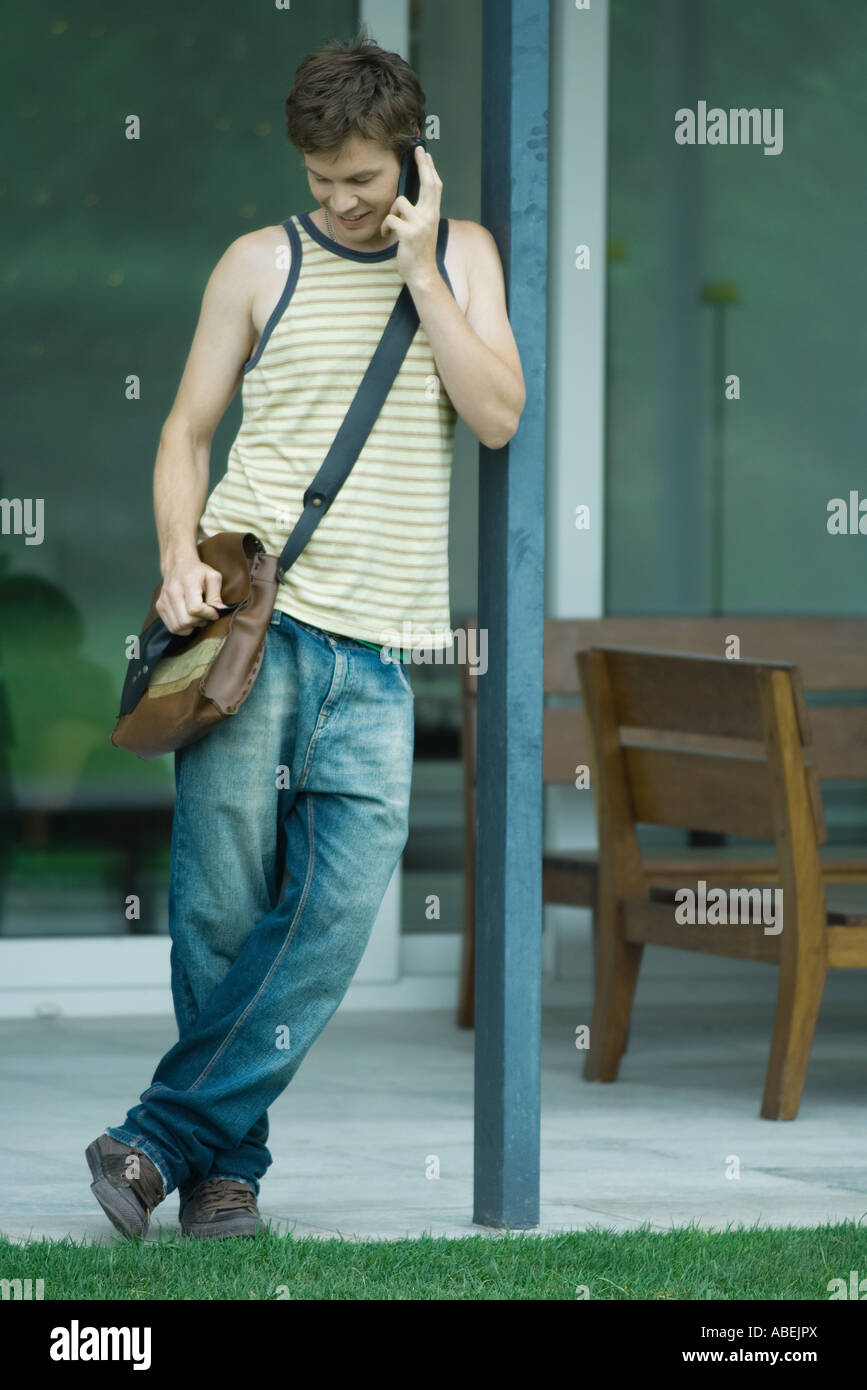 Man leaning on pole, using cell phone, full length Stock Photo Alamy