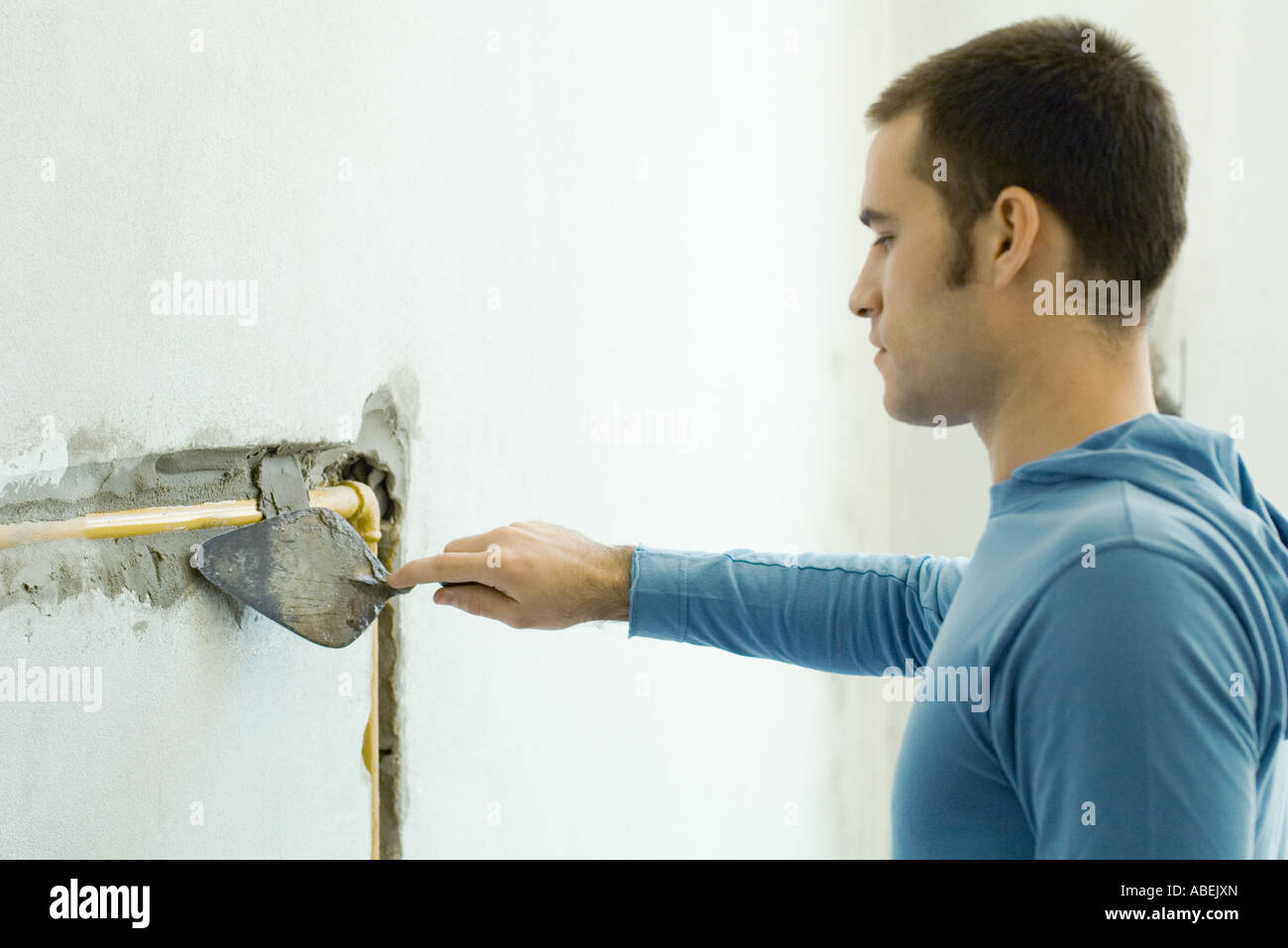 Man filling in hole around plumbing in wall with grout Stock Photo Alamy