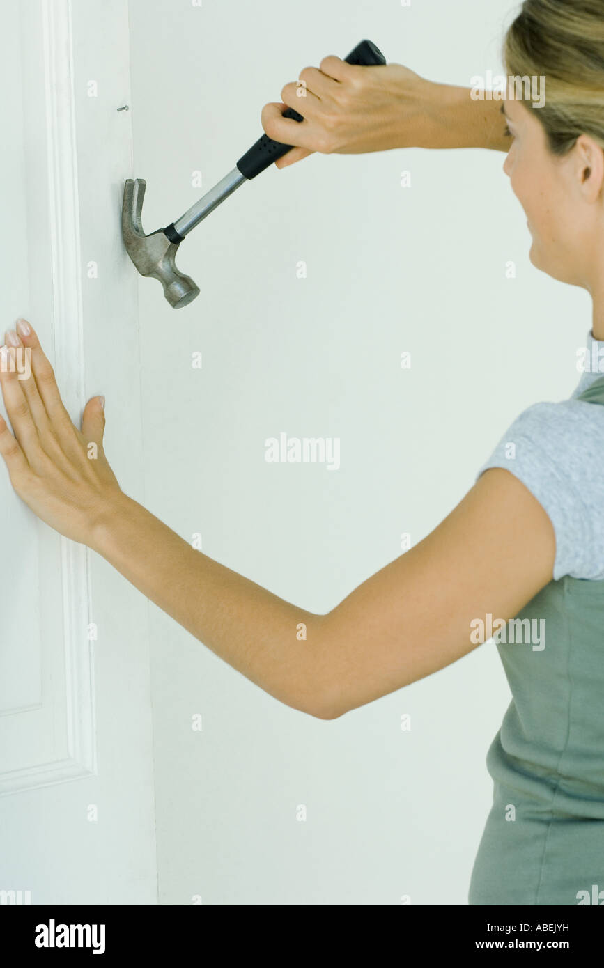 Woman removing nail from wall Stock Photo