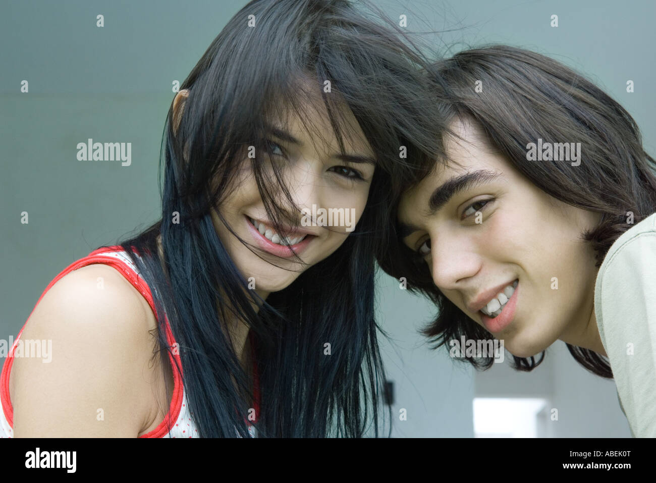 Young couple with heads together, smiling at camera Stock Photo