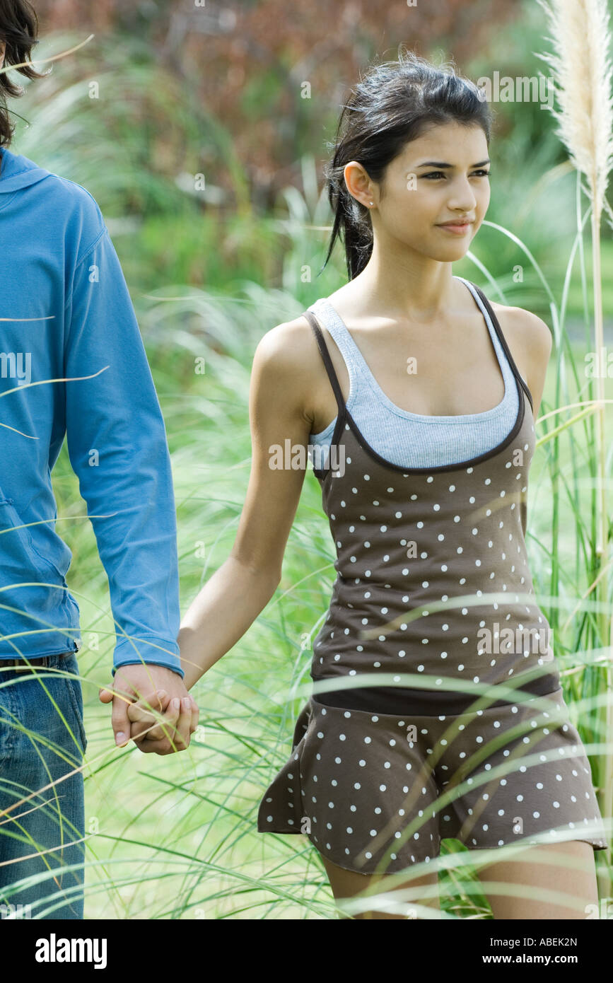 Young couple walking through grass, holding hands Stock Photo - Alamy