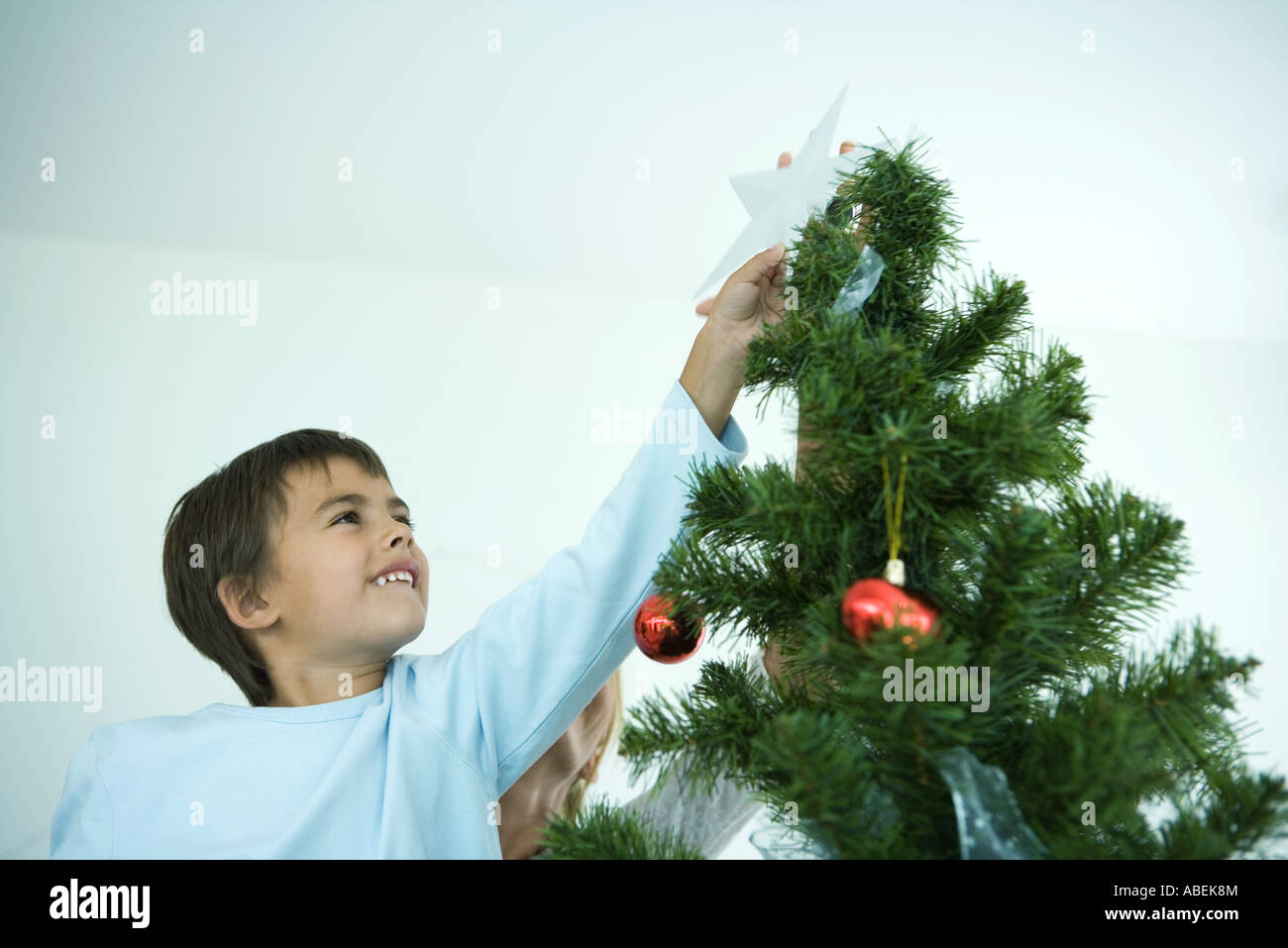 Boy putting star on top of Christmas tree Stock Photo Alamy