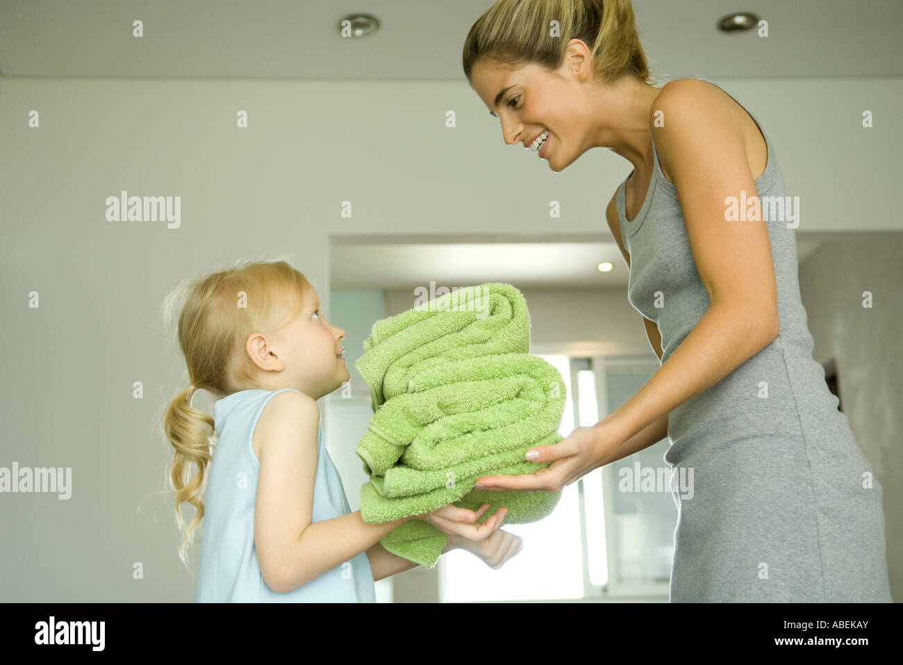 Mother and daughter, girl handing woman stack of towels Stock Photo - Alamy