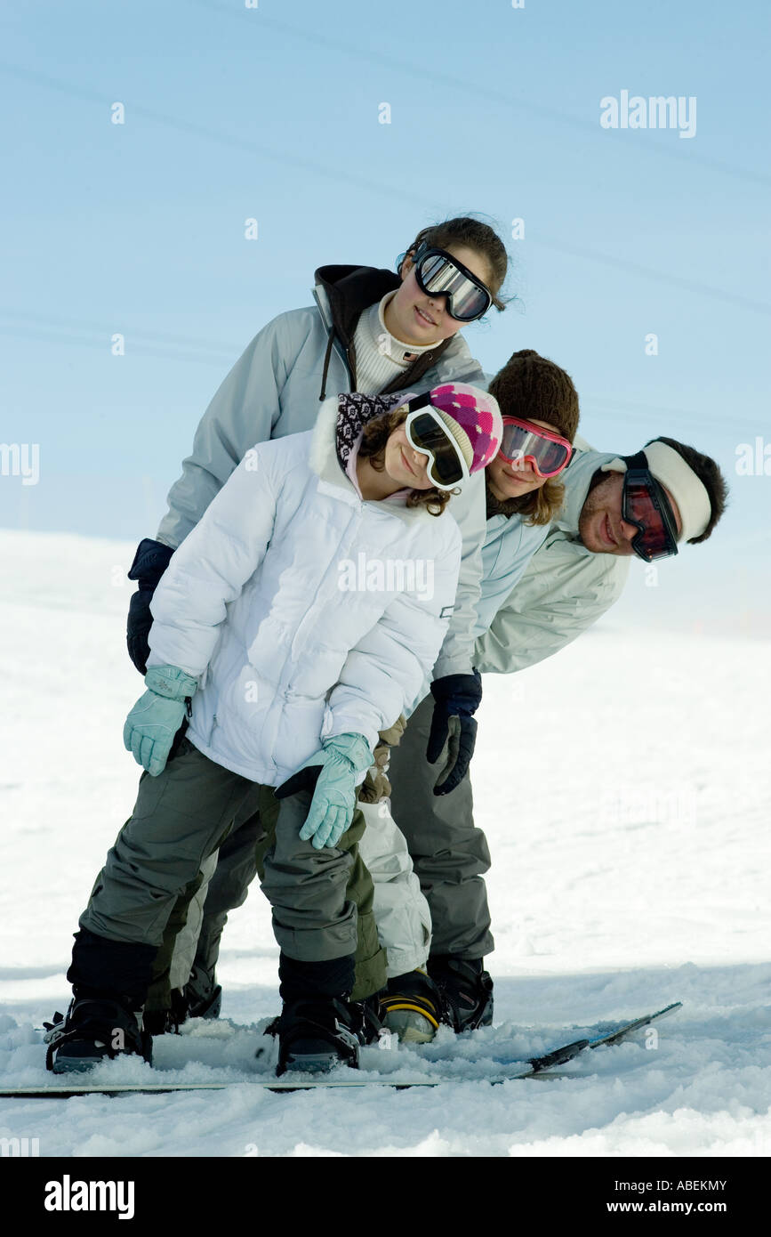 Young skiers standing on ski slope, leaning to the side, full length portrait Stock Photo