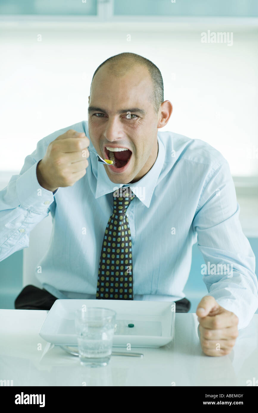 Man using fork to eat vitamins from plate Stock Photo Alamy