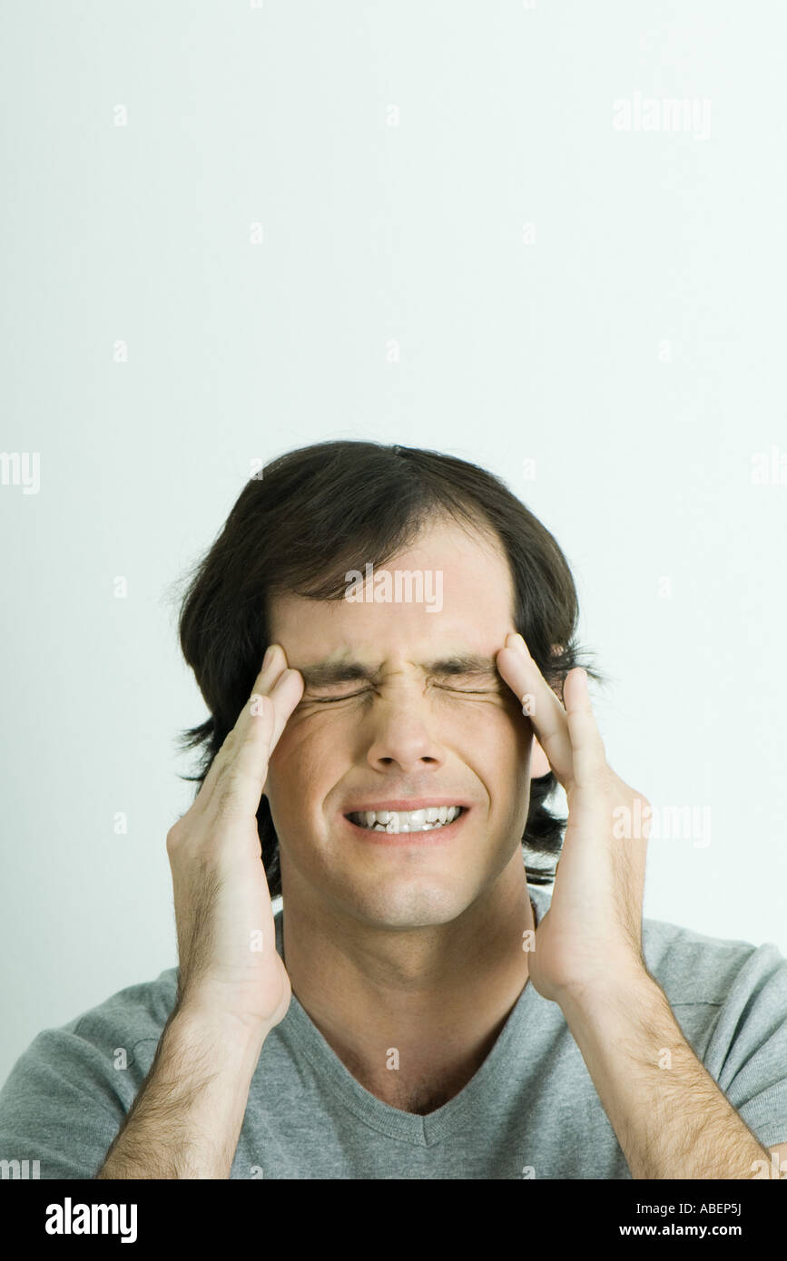 Man, holding sides of head and squinting eyes shut, portrait Stock