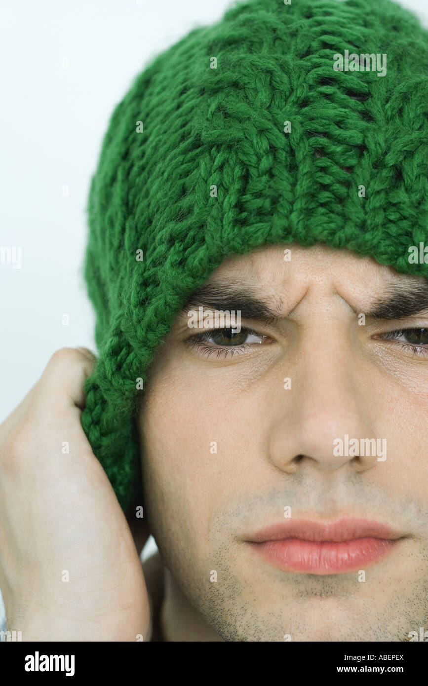 Young man wearing knit hat, furrowing brow, portrait, close-up Stock Photo