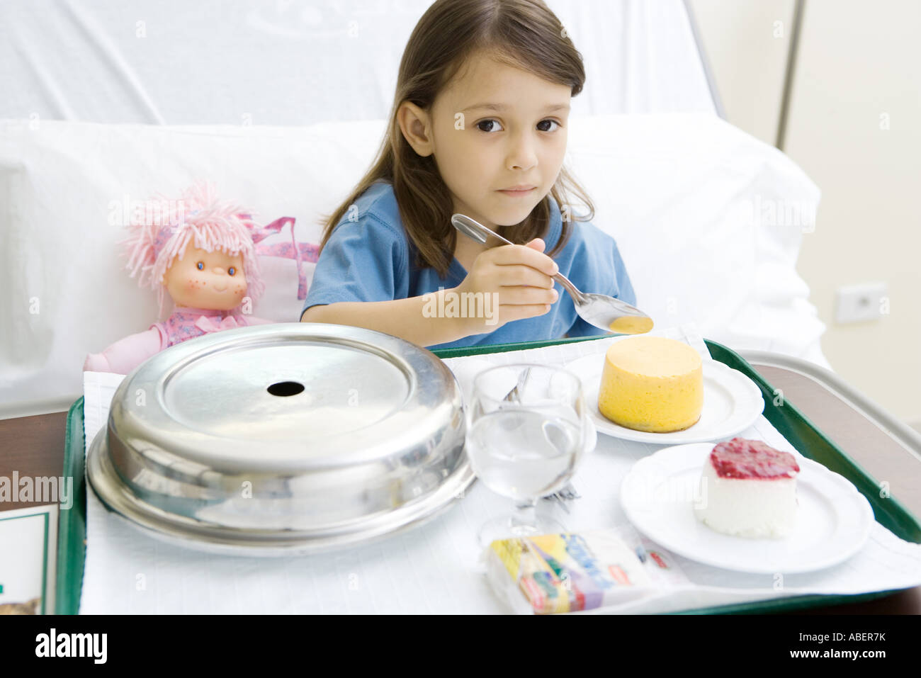 Girl eating meal in hospital bed Stock Photo