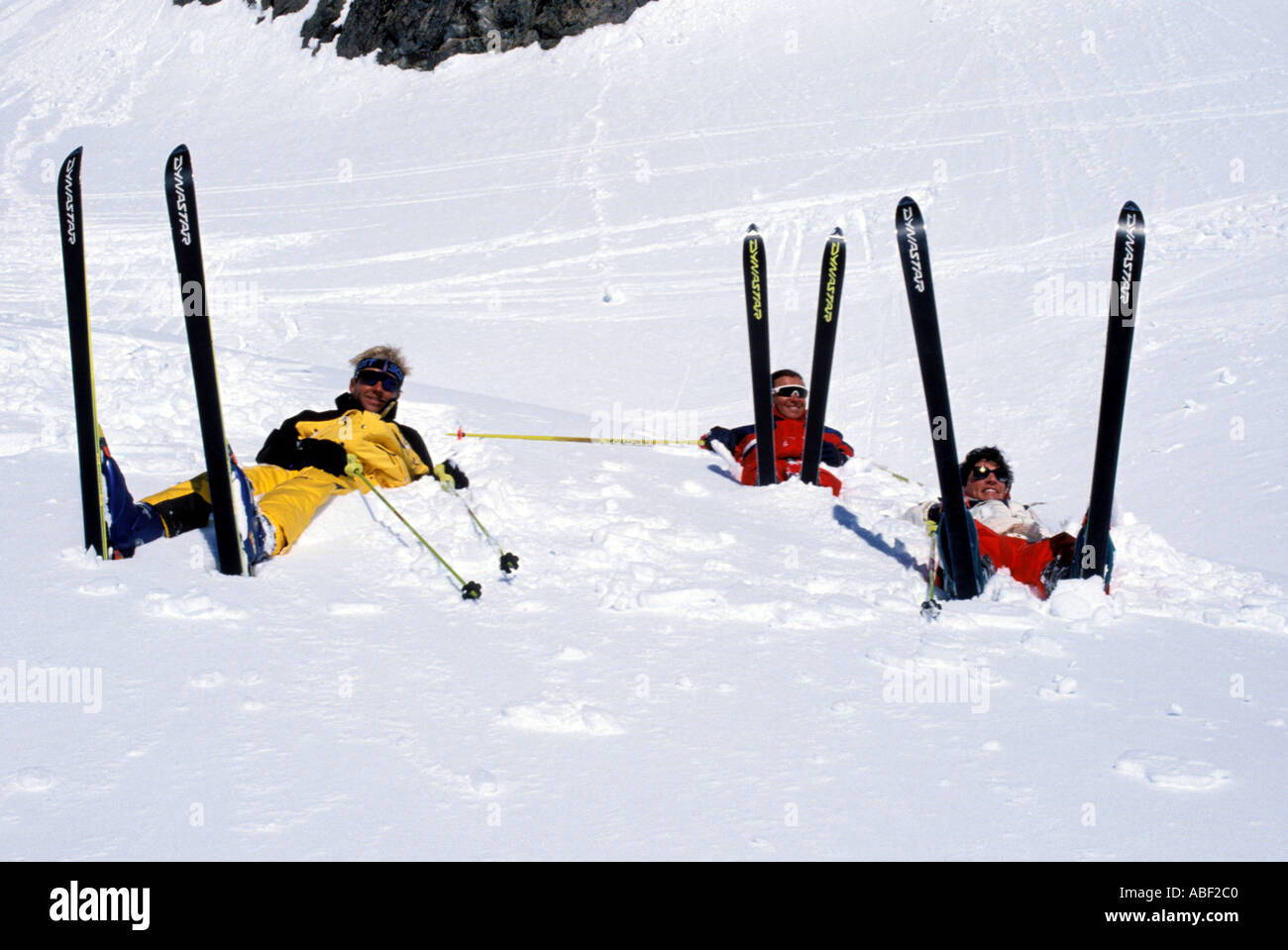 Group of skiers lying back in the deep powder snow with their skis