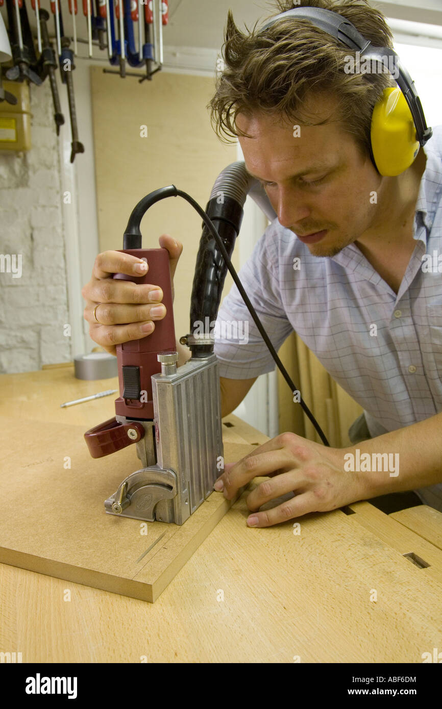 A craftsman uses a biscuit jointer to cut joints in a piece of furniture Stock Photo