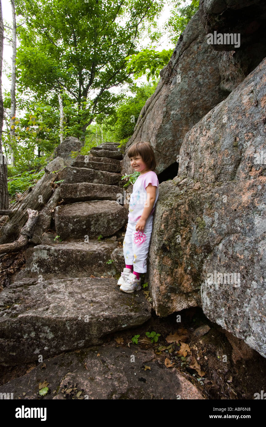 A young girl age 4 on the rock stairs of Kurt Diederich s Trail on Dorr Mountain in Maine s Acadia National Park Stock Photo