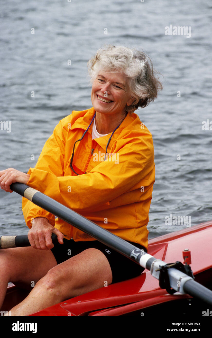 A smiling senior woman rower rests on her oars during a workout Stock ...