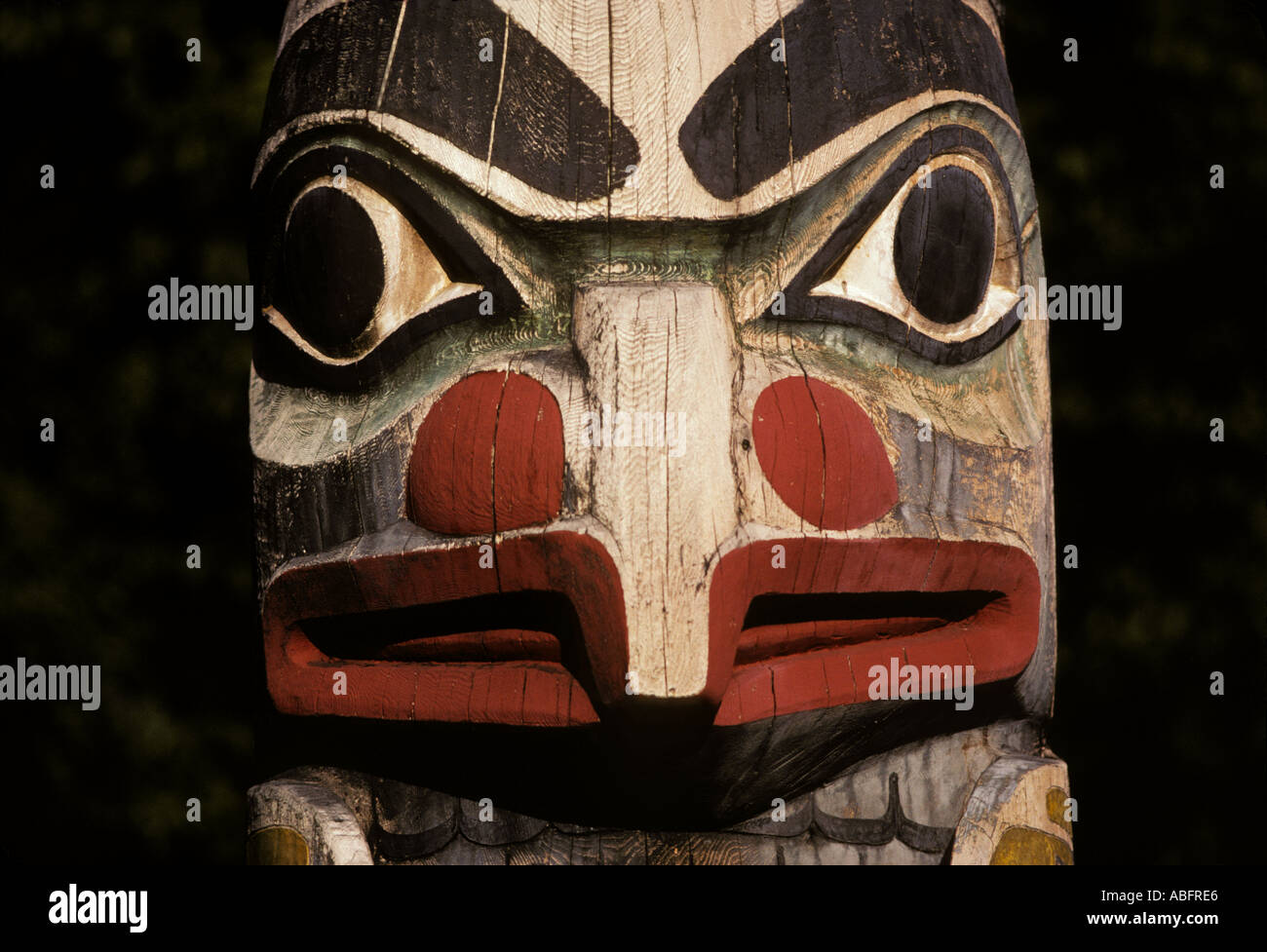 This photograph features a face on a totem pole in Southeast Alaska ...