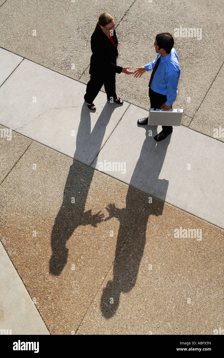 Businessman and woman with shadows meeting with a handshake from above Stock Photo