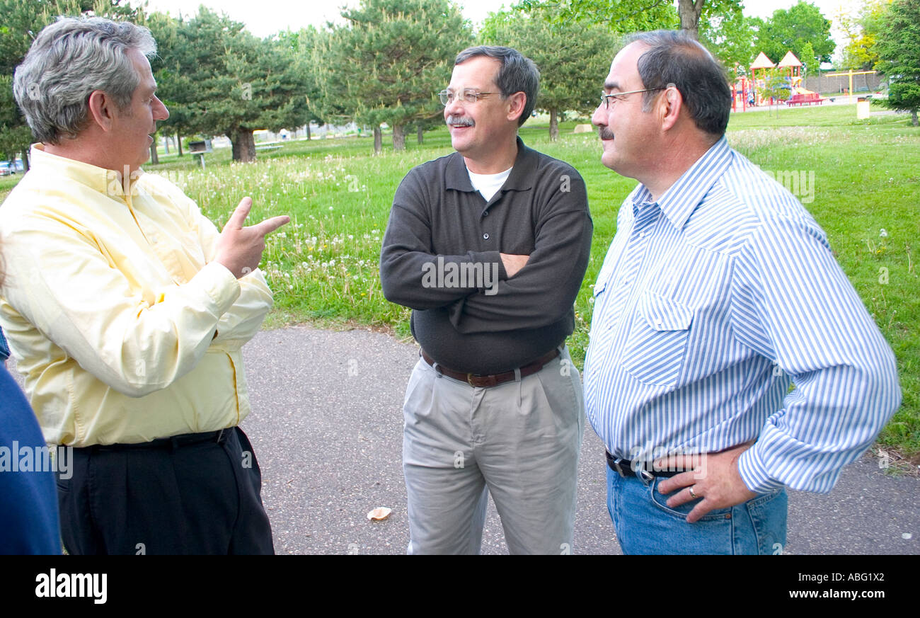 Three men age 50 deep in conversation at community celebration. Dunning Field St Paul Minnesota MN USA Stock Photo
