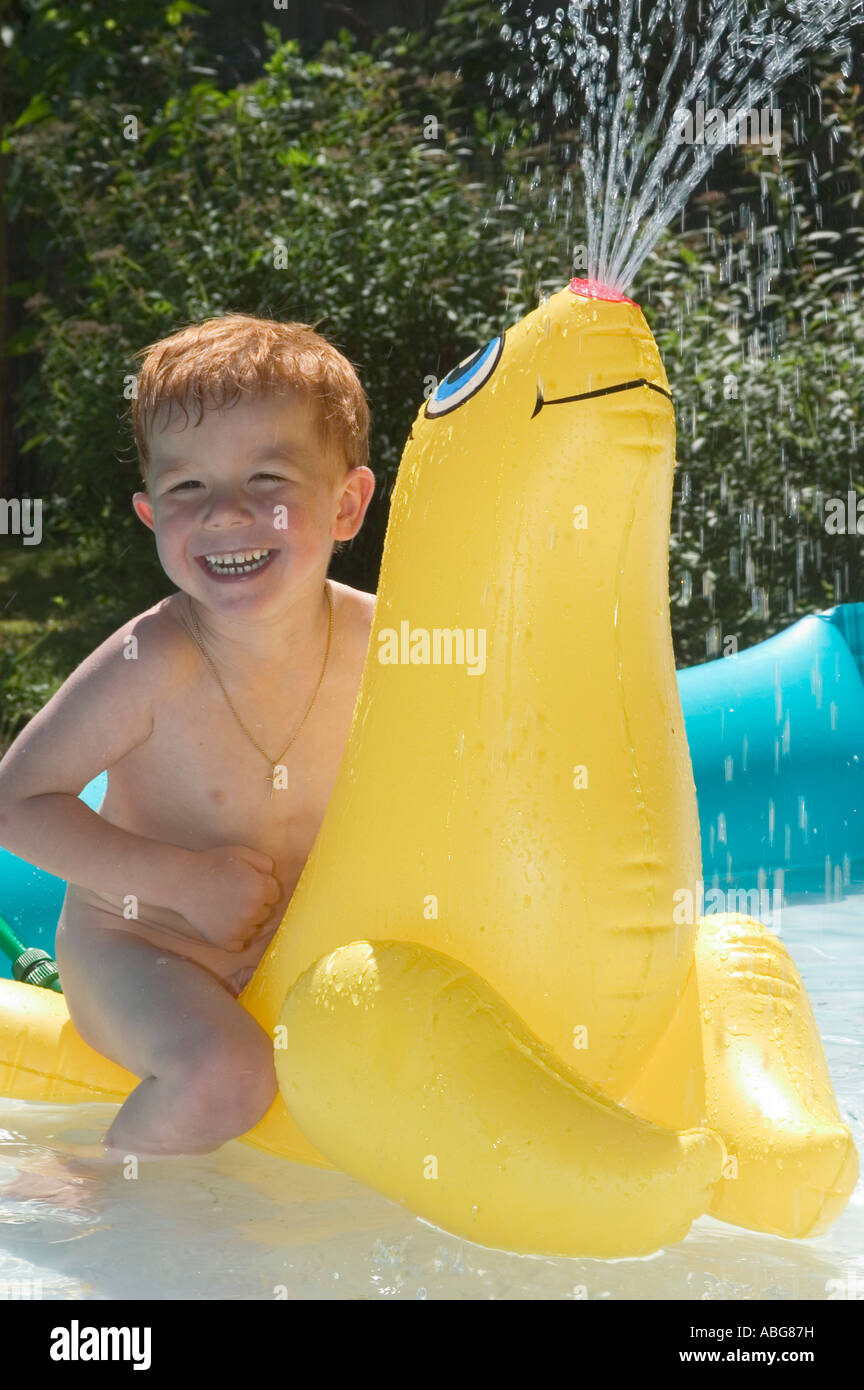 Little boy is playing and splashing with inflatable water animals in