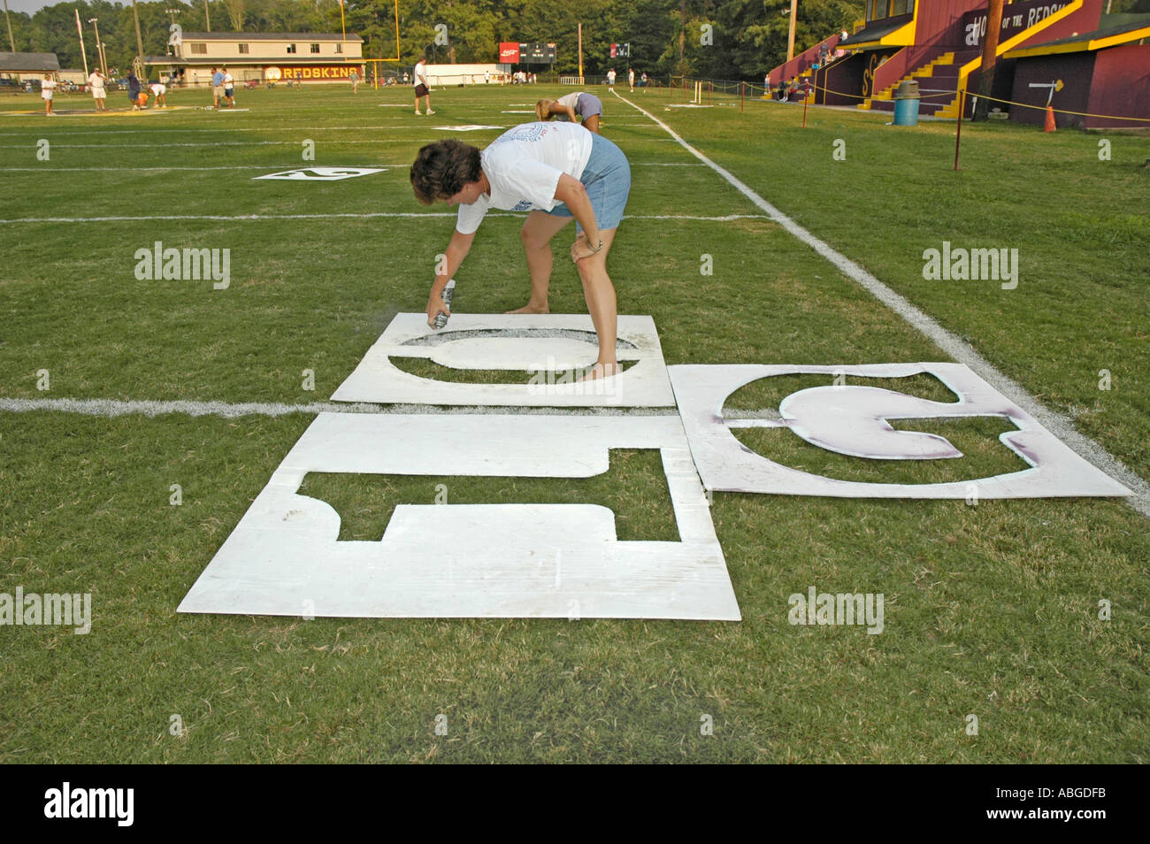 Volunteers Painting yardage numbers and logos on football fields in