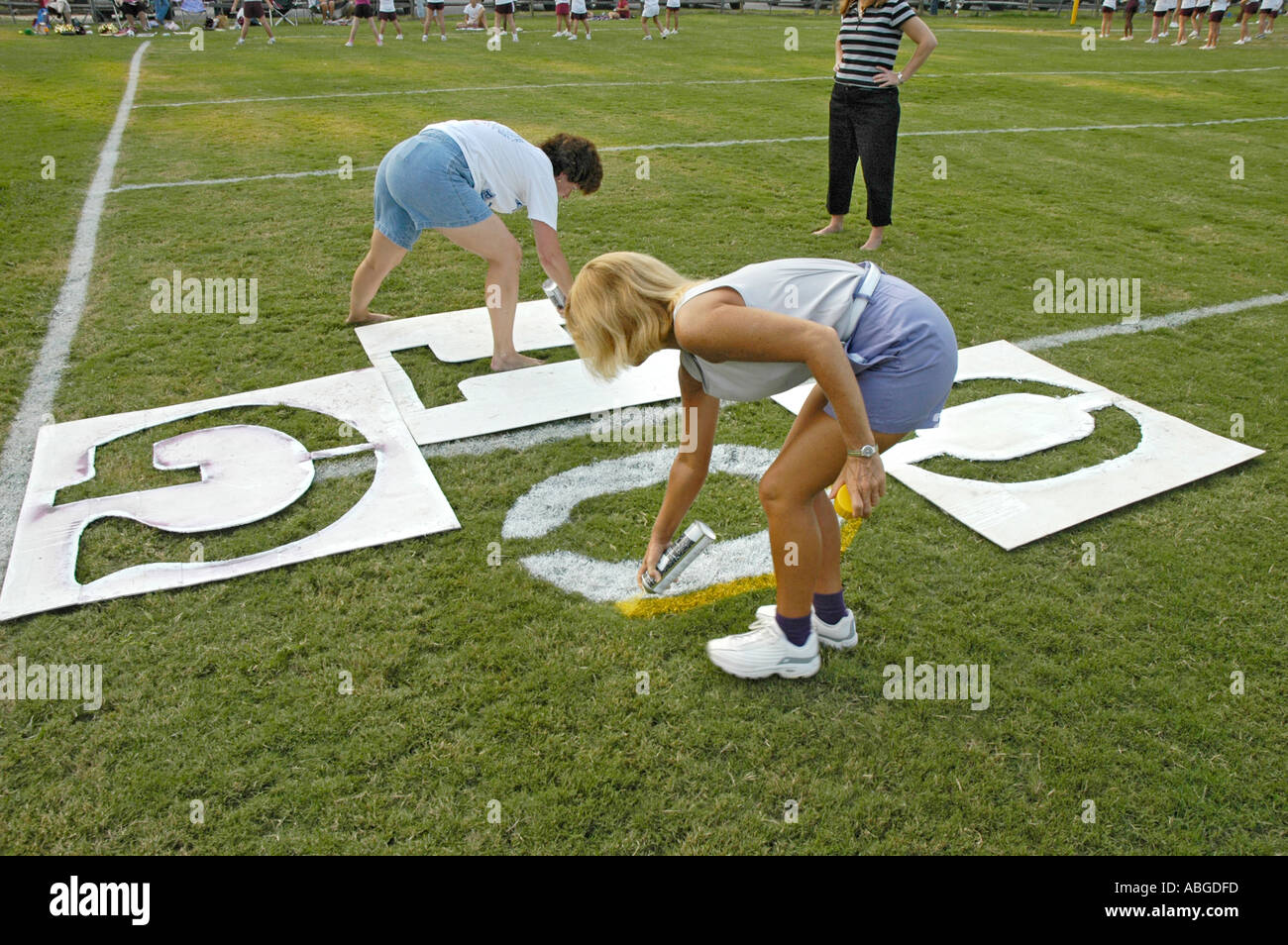 Volunteers Painting yardage numbers and logos on football fields in