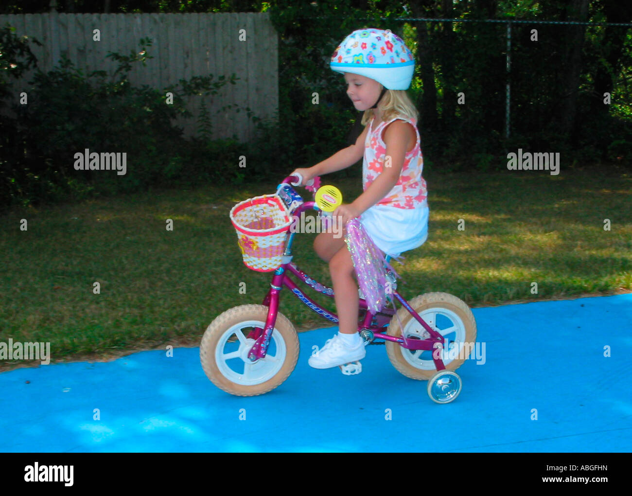Child riding a bicycle with training wheels Stock Photo Alamy