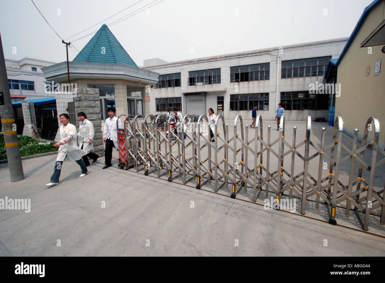A group of factory workers in white robes leave the plant for their lunch break in Shanghai China Stock Photo