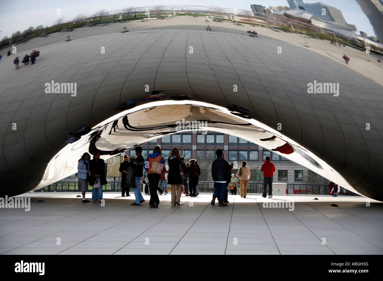 People standing underneath the Cloud Gate Sculpture in Chicago Illinois USA Stock Photo