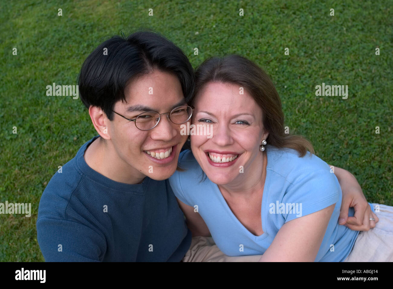 Interracial couple sitting on a lawn in a park Stock Photo