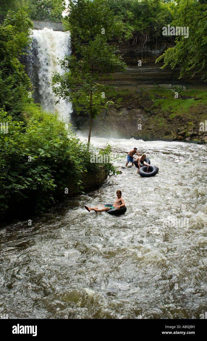 People innertubing down a river with a waterfall in the background