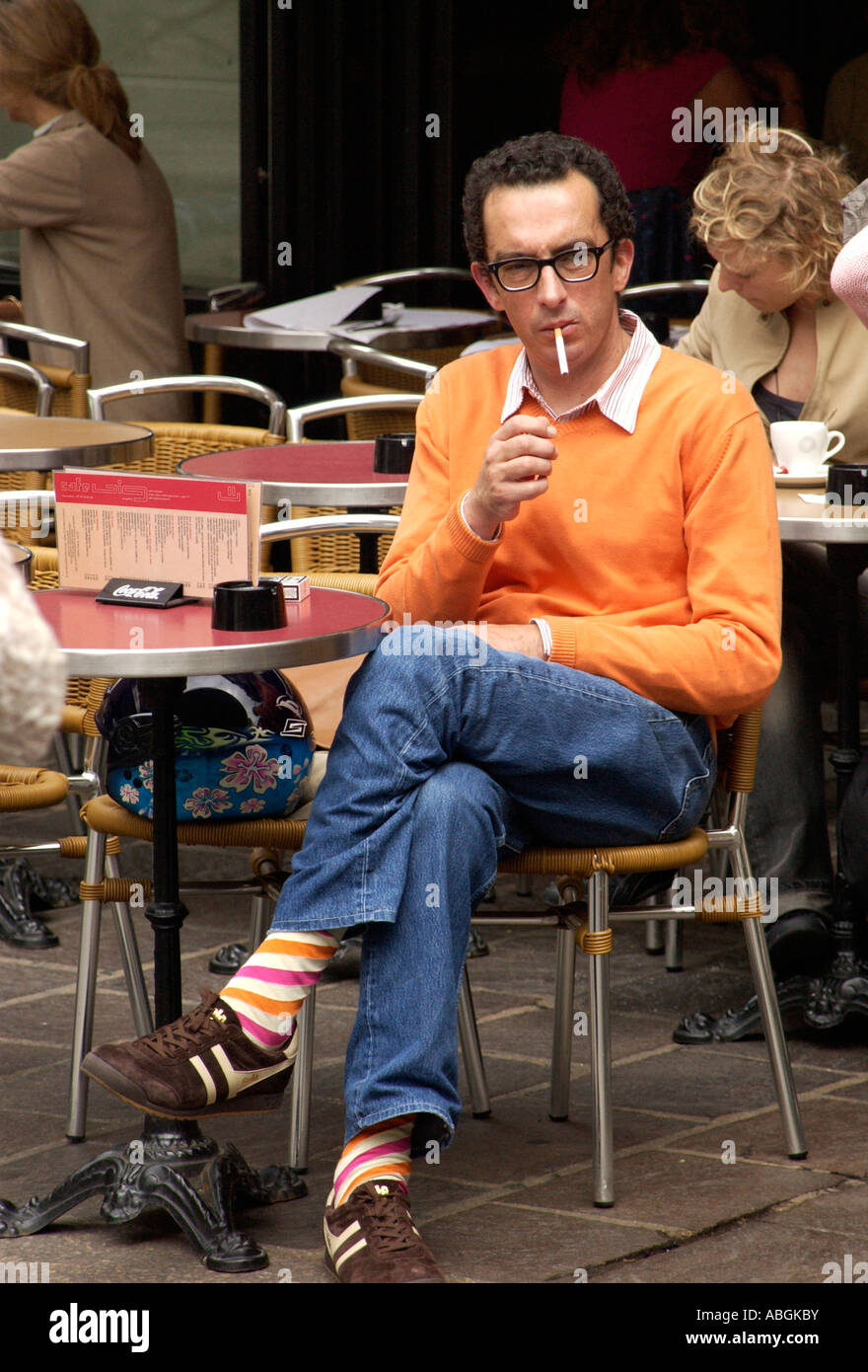A man sits in smoking in a cafe in the Marais in Paris France Stock