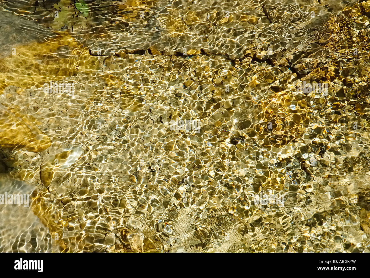 Rippling waves of a mountain brook generates light interferences in cristall clear water Stock Photo