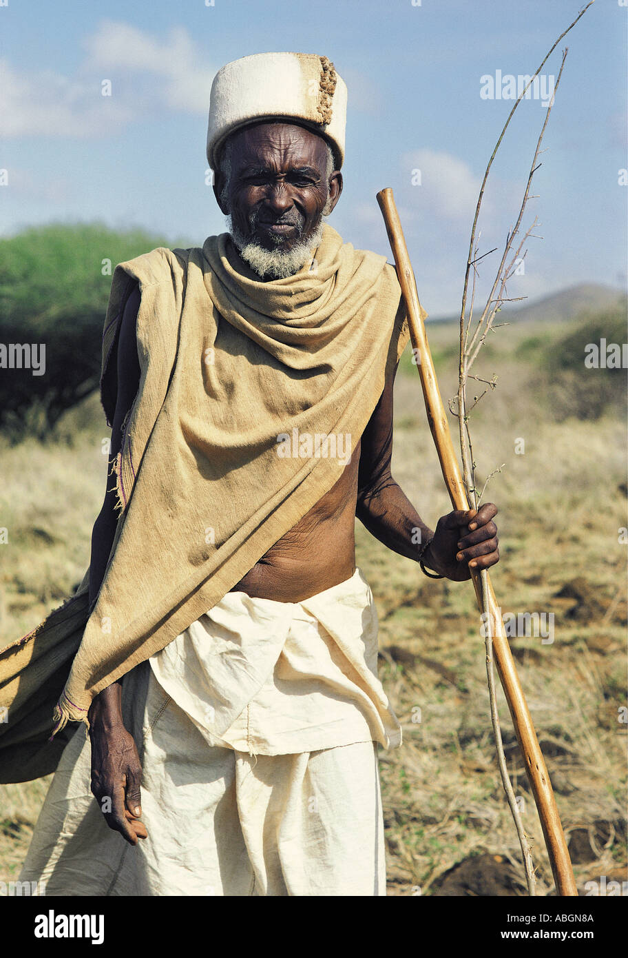 Old Gabbra man holding a wooden stick spear silhouetted against a blue sky Stock Photo