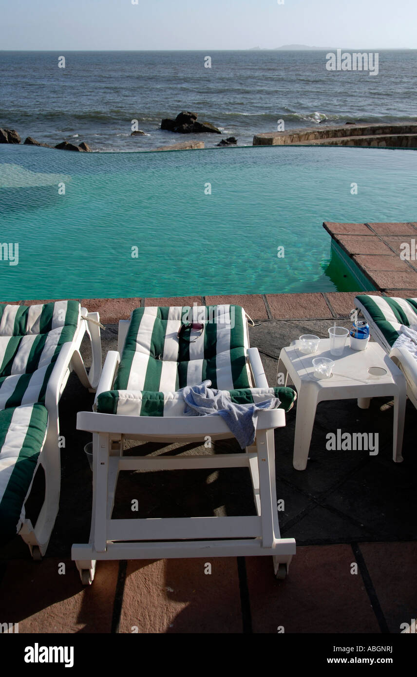 Lounge chairs by a pool and the ocean Stock Photo - Alamy