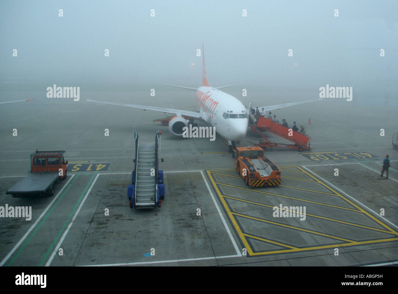Luton airport fog lifting & passengers boarding Easyjet jet aircraft after weather delayed taking off schedules due to poor visibility Bedfordshire UK Stock Photo