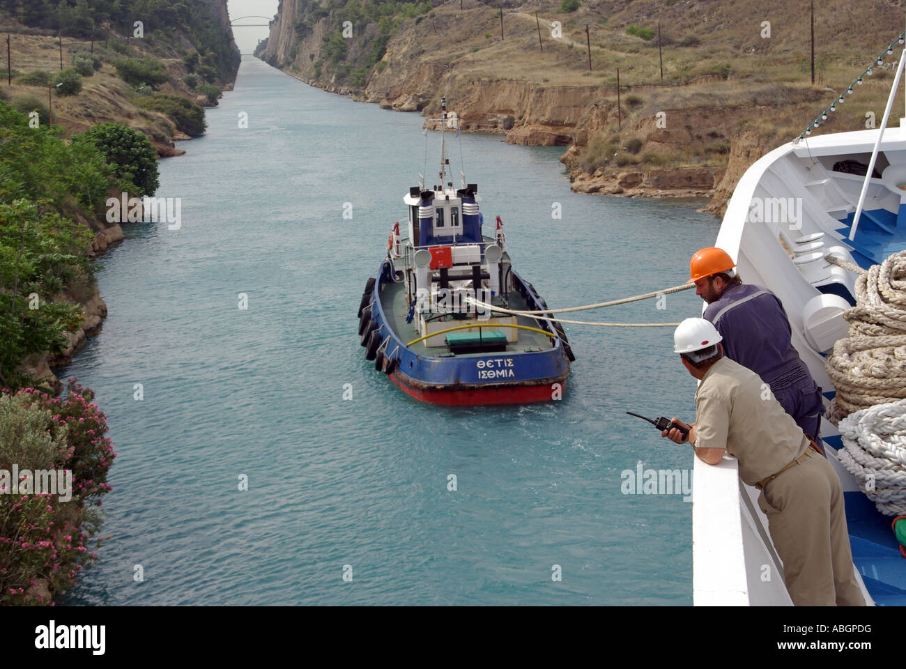 Bow view onboard cruise ship liner crew supervising passage along  narrow Corinth Canal assisted by tug boat Peloponnese peninsula in southern Greece Stock Photo
